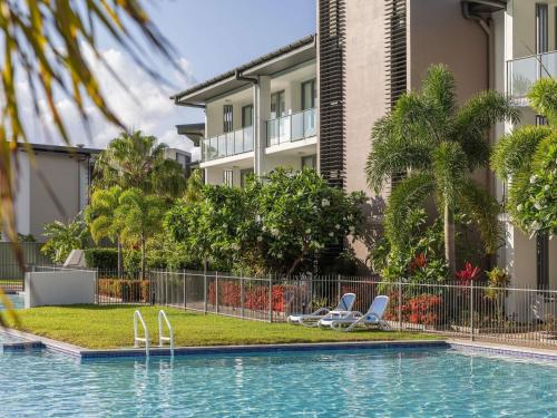 a swimming pool with chairs in front of a building at Peppers Blue on Blue in Nelly Bay