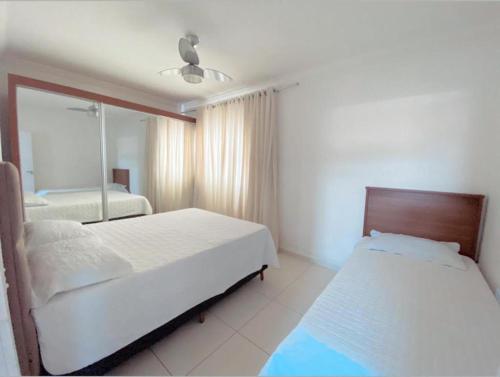 a bedroom with two beds and a mirror at Green House Apartamentos in Ubá