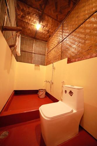 a bathroom with a white toilet in a room at Bali Bamboo Resort in Padinjarathara