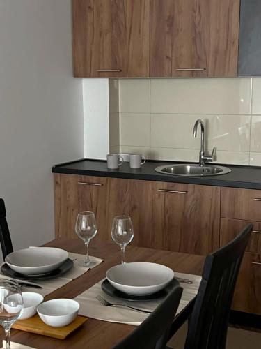 a wooden table with plates and wine glasses on it at Apartments & rooms Concept Nordica in Žabljak