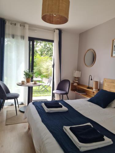 a bedroom with a bed and a table with chairs at Escale à Kergrenn in Fouesnant