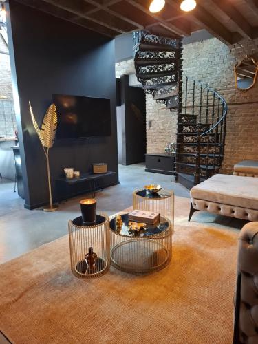 a living room with two tables and a tv and a couch at L'entrepôt Spadois in Spa