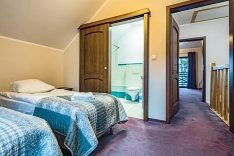 a bedroom with two beds and a door to a bathroom at Apartamenty Niegocin in Wilkasy