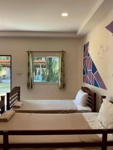 a bedroom with three beds and a window at P&G leampom hotel in Ban Chao Nam