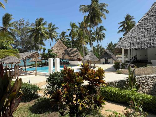 a resort with a swimming pool and palm trees at Amani Palms by Manolo Beach Resort in Uroa