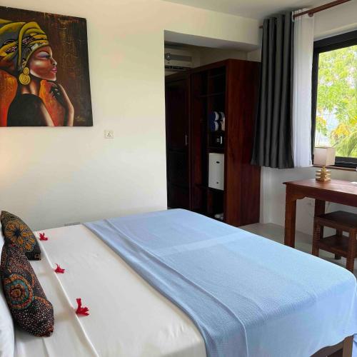 a bedroom with a bed with a painting on the wall at Amani Palms by Manolo Beach Resort in Uroa