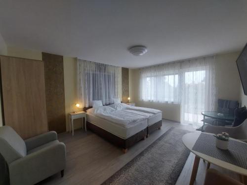 a bedroom with a bed and a couch and a chair at Anton Apartmanház in Balatonfüred