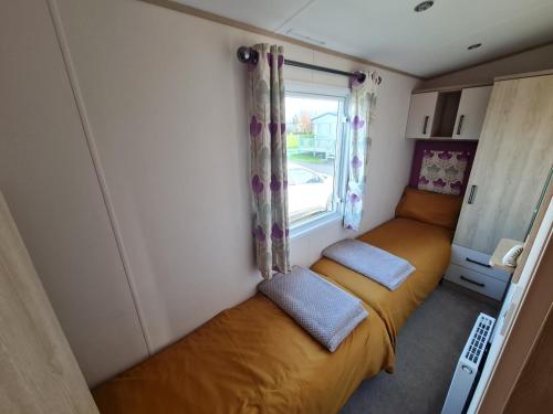 a small bedroom with a bed in a caravan at Lilly Luxury Hot Tub Caravan - theluxurycaravan - GV109 Grange Leisure Park in Mablethorpe