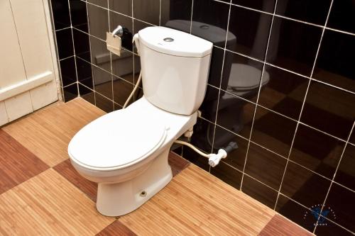 a white toilet in a bathroom with black tiles at The Change Hotel in Kandy