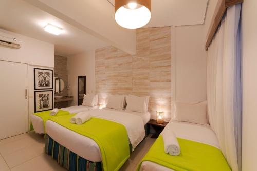 a bedroom with two beds with green and white sheets at Pousada da Villa in Fernando de Noronha