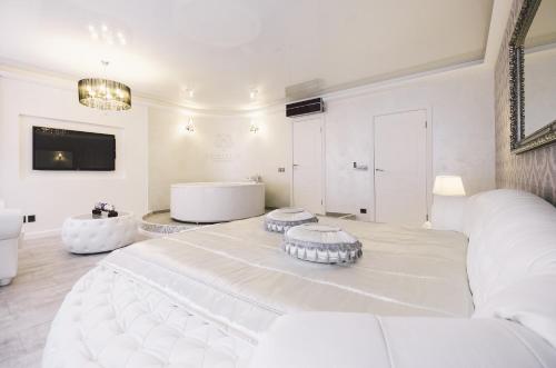 Cette chambre blanche comprend un grand lit et une baignoire. dans l'établissement Jacuzzi Romantic Apartment, à Klaipėda
