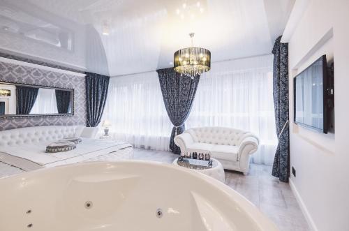 a large white bathroom with a tub and a couch at Jacuzzi Romantic Apartment in Klaipėda