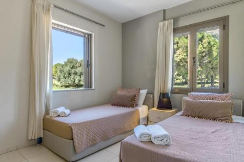 two beds in a room with two windows at G.Living 365 in Agia Effimia