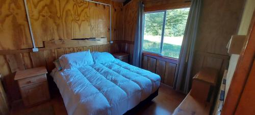 a large bed in a room with a window at Cabañas Entre Mañios y Coigües in Villa Santa Lucía