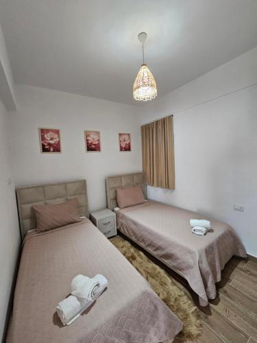 a bedroom with two beds and a chandelier at Rafa's Apartament in Himare