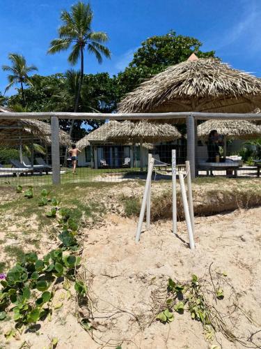 a straw umbrella and a chair on the beach at Pousada Farol das Tartarugas in Praia do Forte