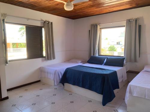 two beds in a room with two windows at A passos do paraíso!! in Lauro de Freitas