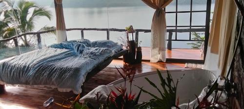a bed in a room with a large window at Nhà Bên Hồ in Bảo Lộc