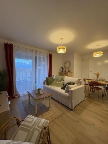 a living room with a white couch and a table at Ecrin de nacre Appartement de Standing in Courseulles-sur-Mer