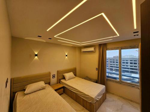 a bedroom with two beds and a large window at Salalah Apartment in Cairo
