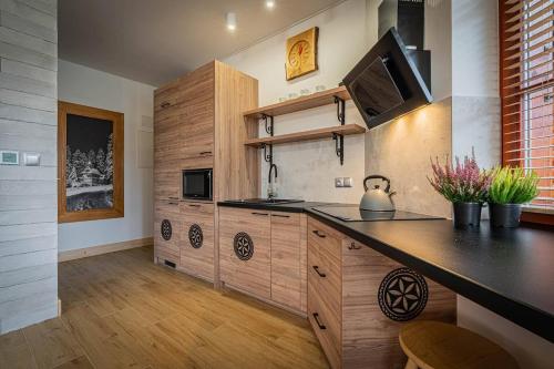 a kitchen with wooden cabinets and a counter top at Good Morning Giewont & JACUZZI in Kościelisko