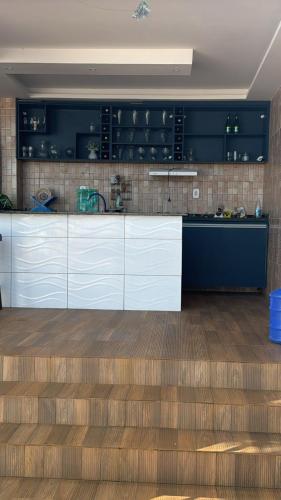 a kitchen with white cabinets and a wooden floor at Temporada Monte gordo in Camacari