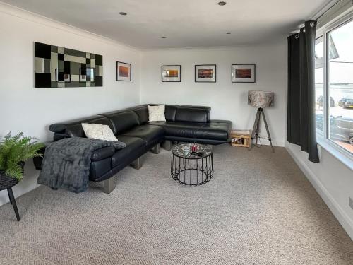 a living room with a black leather couch and a window at Thirslet in Maldon