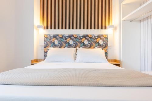 a bedroom with a white bed with a painting on the wall at Hotel Lo Scoglio in Porto Cesareo