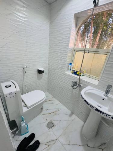 a white bathroom with a toilet and a sink at Velmora Cozy 2BR Apartment 20 in Abu Dhabi