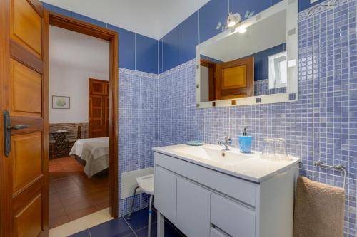 a blue tiled bathroom with a sink and a mirror at Casa Flor do Mar Lagos in Lagos