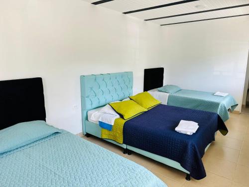 a bedroom with two beds with blue and yellow sheets at HOTEL DEL MINERO Otanche in Otanche