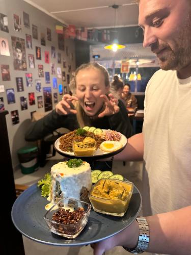 a man holding a tray of food on a table at Ella Ceylon Homies Hostel in Ella