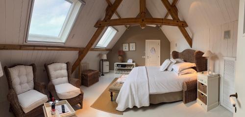 a bedroom with a bed and two chairs in a attic at La Luna Guesthouse in Bruges