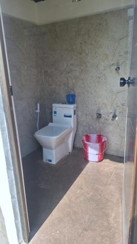 a bathroom with a toilet and a red bucket at Secret valley vattavada in Vattavada