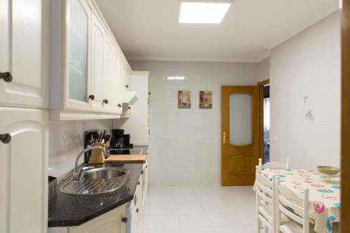 a white kitchen with a sink and a table at Casa rural El Laurel in Chañe
