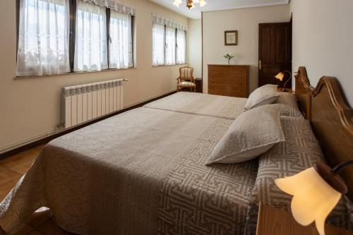 a bedroom with a large bed in a room with windows at Apartamentos Carolina in Celorio