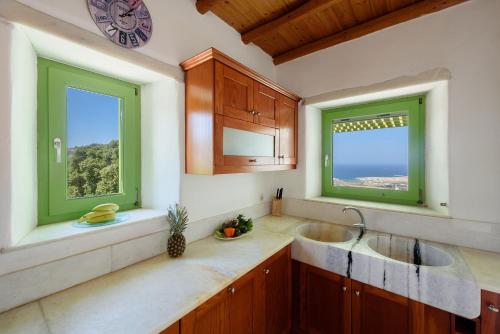a kitchen with two sinks and two windows at Villa Aeolos with 2 private pools in Sarakíniko