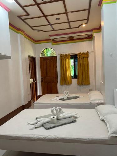 two beds with towels and a cup on top of them at Austrias Guest House in El Nido