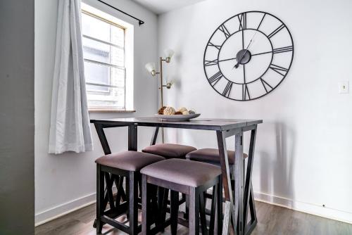 a dining room table with stools and a clock on the wall at Jungle House Luxury Homes - Columbus Downtown Short North - Steps to Convention Center & Nationwide Arena - Sleeps up to 6 - Free Parking - Over 5,800 Five Stars in Columbus