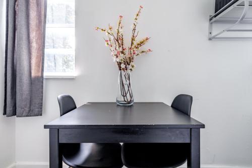 a vase of flowers on a table with chairs at Jungle House Columbus Downtown Free Parking Sleeps 6 - Steps to Convention Center & Nationwide Arena - 1BR Short North Luxury Home - Over 5,800 Five Star Stays in Columbus