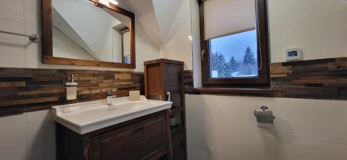 a bathroom with a sink and two windows at Chata Krpko in Horná Lehota