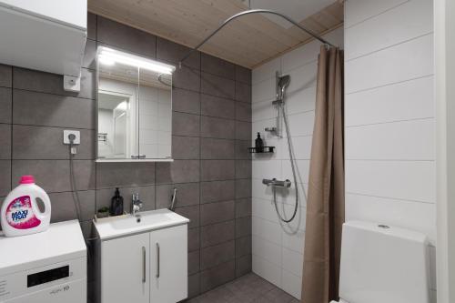 a bathroom with a shower and a sink and a mirror at Pramea Apartments Tourula in Jyväskylä