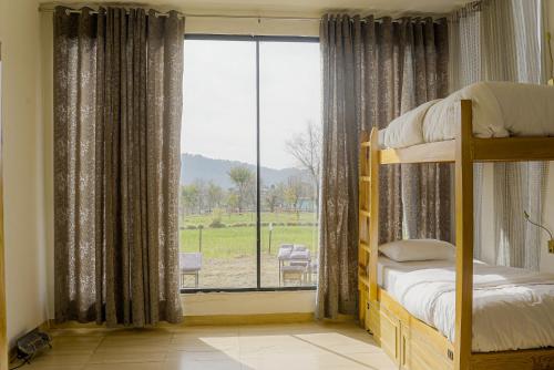 a bedroom with a bunk bed and a large window at Qudrat - Boutique Hostel & Cafe in Bīr