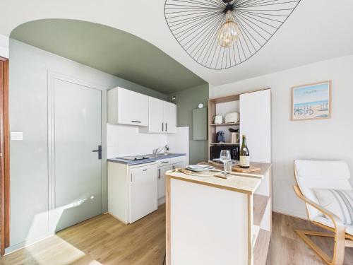 a kitchen with white cabinets and a chandelier at L îlot d Arthur in Île-Tudy