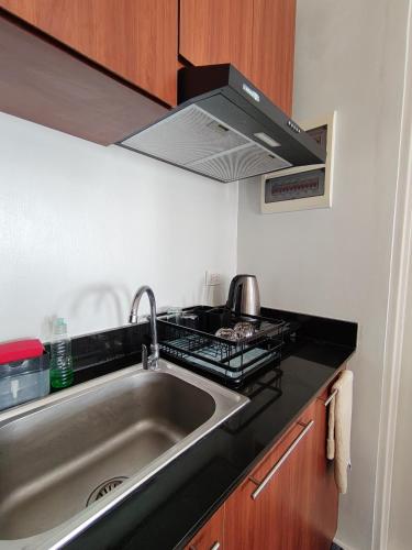 a kitchen with a sink and a stove at Puerto Princesa Studio Condo with 2 Large Beds, Balcony, Pool & Gym in Puerto Princesa City