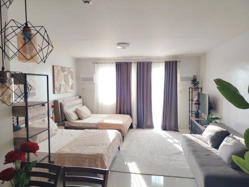 a living room with two beds and a couch at Puerto Princesa Studio Condo with 2 Large Beds, Balcony, Pool & Gym in Puerto Princesa City