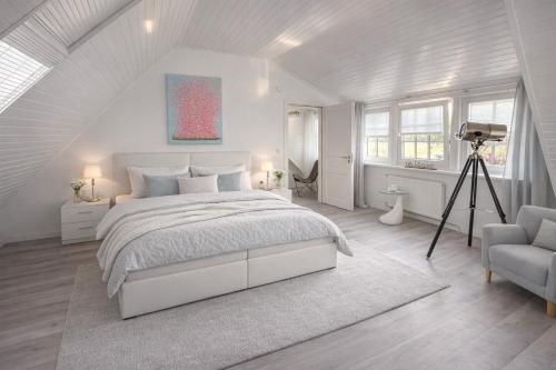 a white bedroom with a bed and a camera at "Huus ant Diek", Ferienhaus mit Maisonette Wohnung in Deichnähe, Nähe Norddeich in Norden
