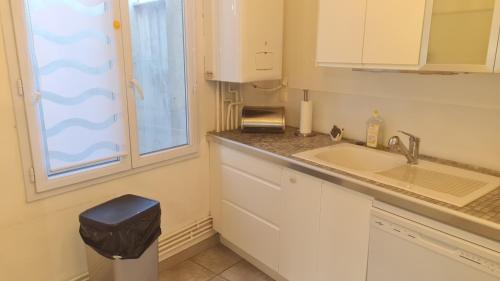 a kitchen with white cabinets and a sink and a window at Appartement Duplex nimes centre160m2 climatisation 3 chambres avec parking in Nîmes