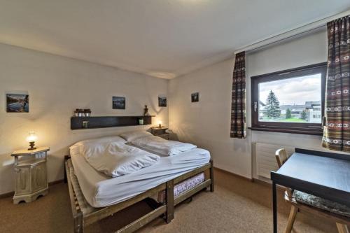 a bedroom with a bed and a desk and a window at Chesa Chamuotsch - Celerina in Celerina