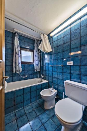 a blue tiled bathroom with a toilet and a sink at Chesa Chamuotsch - Celerina in Celerina